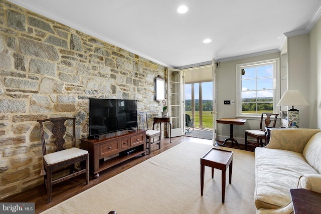 living room featuring crown molding, a stone fireplace, and hardwood / wood-style flooring