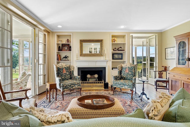 living room featuring built in shelves, light hardwood / wood-style flooring, and crown molding