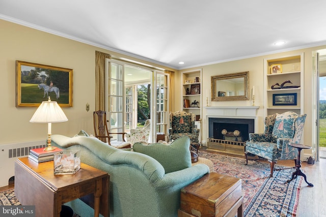 living room with built in features, wood-type flooring, radiator heating unit, and ornamental molding