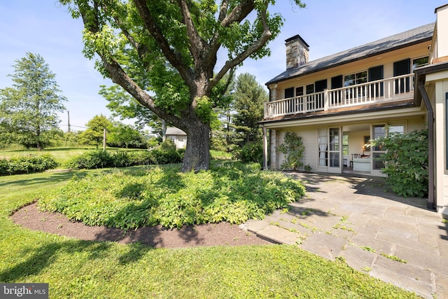 view of yard with a balcony, french doors, and a patio area