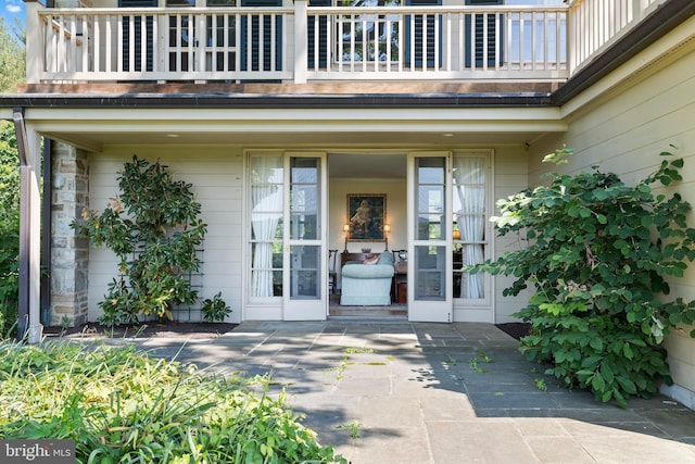 view of exterior entry with a balcony and french doors