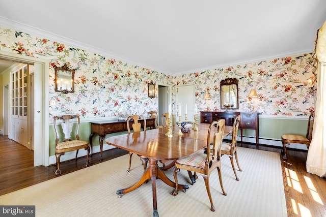 dining area featuring ornamental molding, light wood-type flooring, and a baseboard heating unit