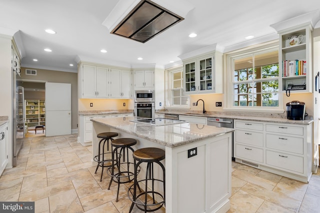 kitchen featuring stainless steel appliances, a center island, white cabinetry, and light stone counters