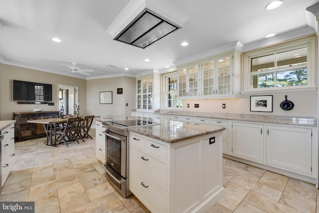 kitchen featuring light stone counters, a kitchen island, crown molding, white cabinetry, and ceiling fan