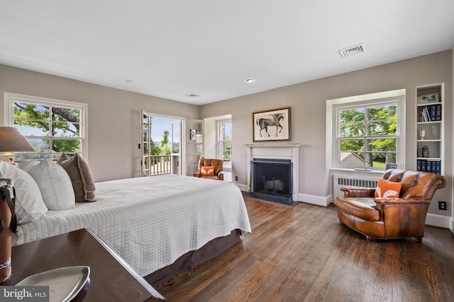 bedroom featuring access to outside, radiator heating unit, and dark hardwood / wood-style flooring