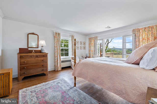 bedroom featuring dark hardwood / wood-style floors, radiator heating unit, and ornamental molding