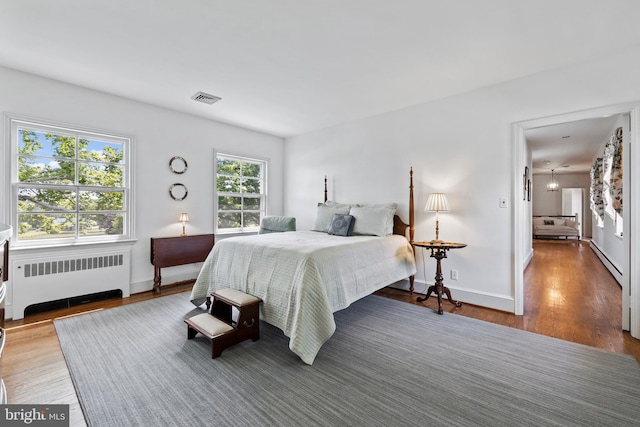 bedroom featuring radiator heating unit, multiple windows, and dark hardwood / wood-style floors