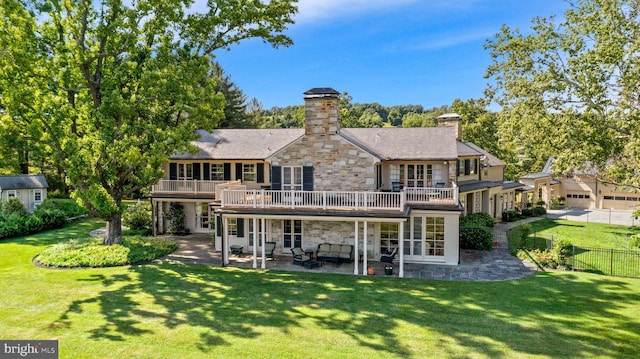 rear view of house featuring a balcony, a lawn, and a patio area