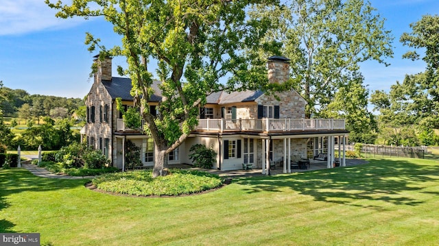 rear view of house featuring a lawn, a balcony, and a patio area