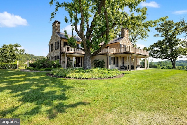 rear view of property with a balcony and a yard