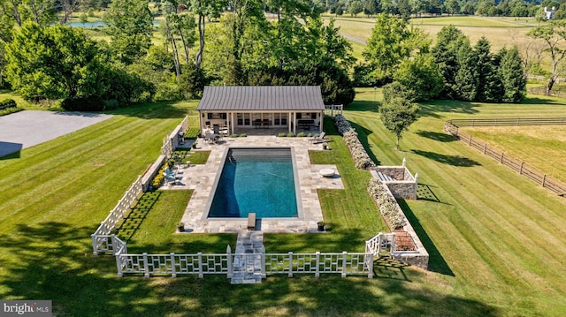 view of swimming pool with a rural view, a diving board, and a lawn