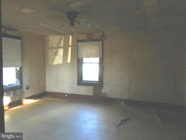 unfurnished room with ceiling fan and concrete flooring