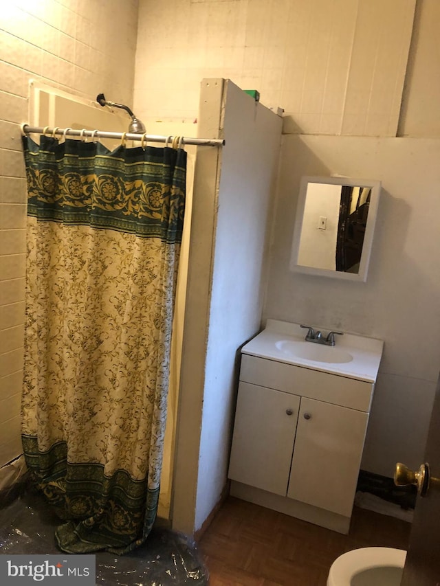 bathroom with toilet, parquet flooring, and vanity