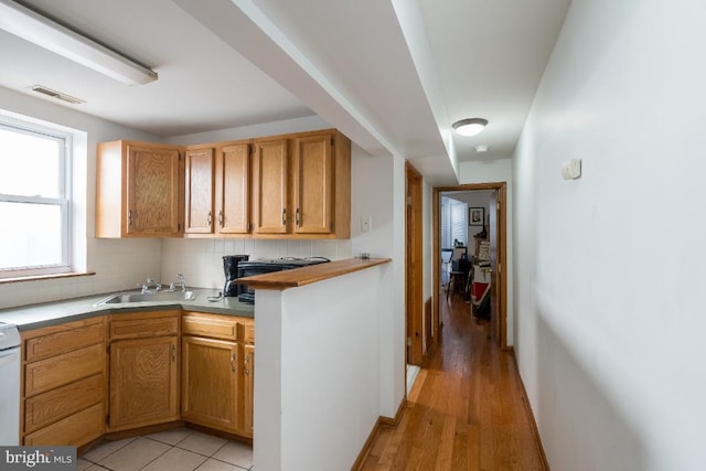 kitchen featuring sink, backsplash, range, and light tile flooring