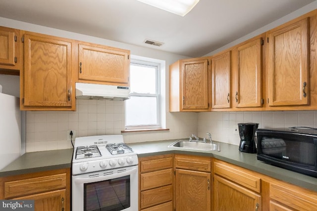 kitchen featuring backsplash, white appliances, and sink