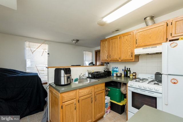 kitchen featuring tasteful backsplash, light tile floors, plenty of natural light, white appliances, and sink