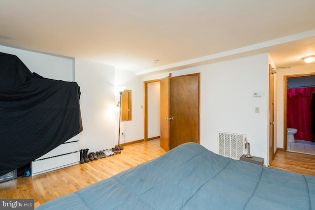 bedroom with ensuite bathroom and light tile floors