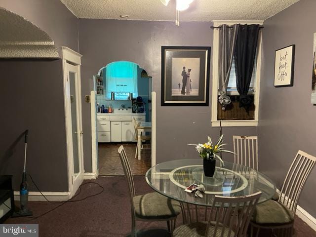 carpeted dining space featuring a textured ceiling