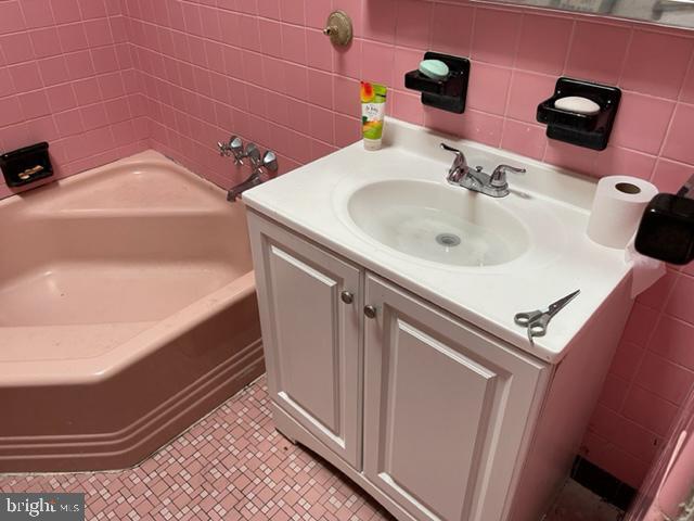 bathroom featuring tile walls, tile flooring, vanity, and shower / tub combination