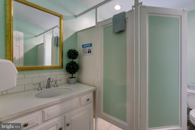 bathroom featuring tile floors, vanity, toilet, and tasteful backsplash