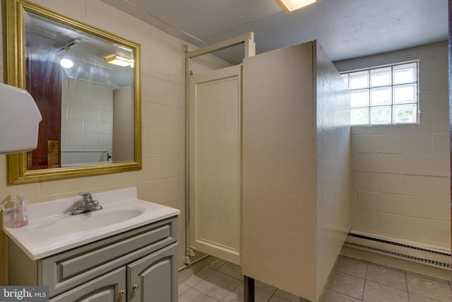 bathroom with tile floors, vanity, and baseboard heating