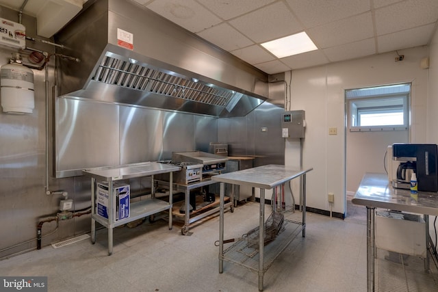 interior space featuring stainless steel counters, a drop ceiling, and light tile flooring