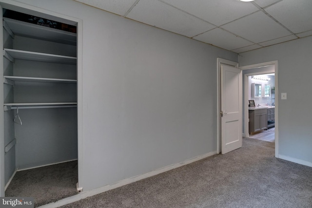 unfurnished bedroom featuring a paneled ceiling, carpet, and a closet