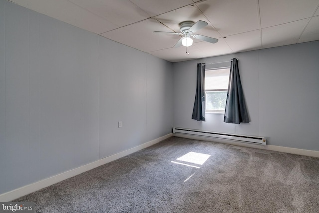 carpeted empty room featuring ceiling fan, a baseboard heating unit, and a paneled ceiling