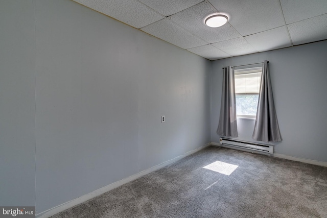 empty room with carpet, a baseboard radiator, and a drop ceiling