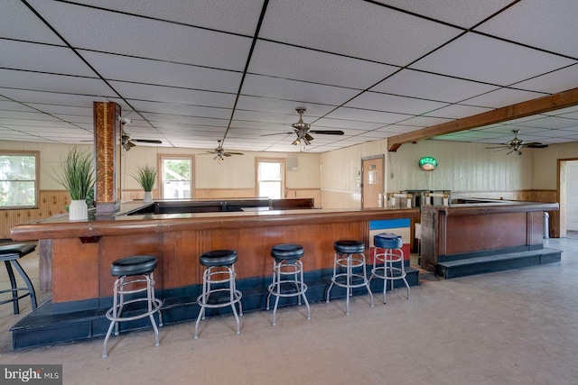 bar with tile floors, ceiling fan, and a paneled ceiling