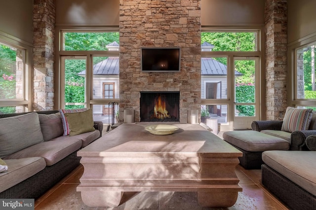 living room featuring tile floors, a stone fireplace, and a towering ceiling