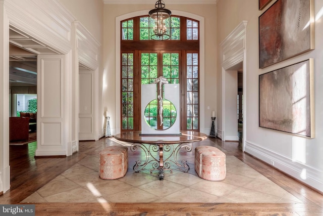 entrance foyer featuring an inviting chandelier, crown molding, a high ceiling, and hardwood / wood-style flooring