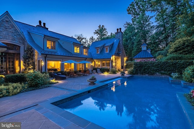 pool at dusk featuring a patio