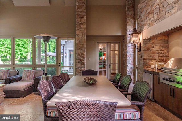 dining room with french doors, an inviting chandelier, light tile flooring, and a towering ceiling