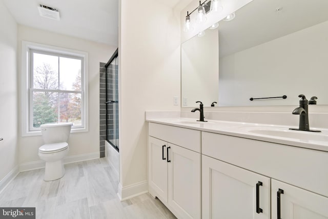 full bathroom featuring shower / bath combination with glass door, vanity, and toilet