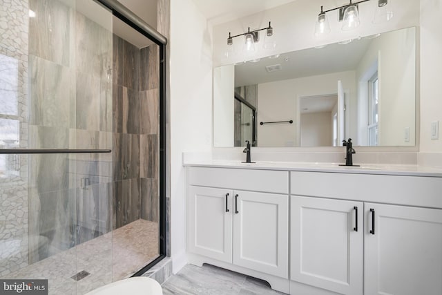 bathroom featuring a shower with door and vanity