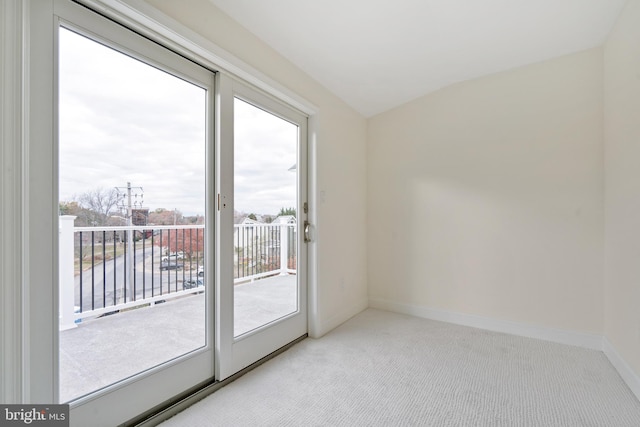 doorway to outside featuring light colored carpet and vaulted ceiling