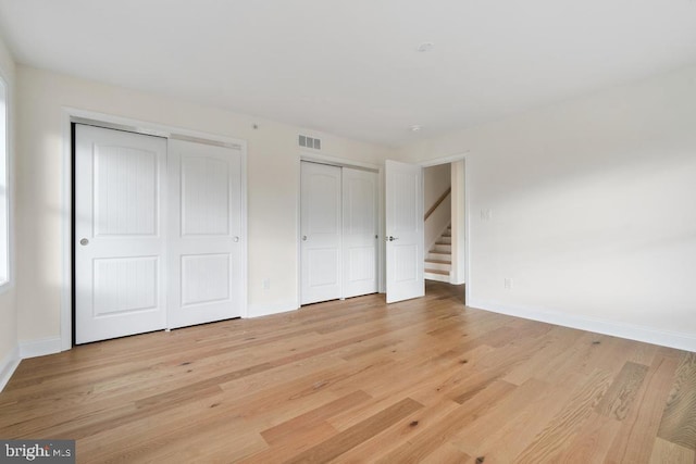 unfurnished bedroom with multiple closets and light wood-type flooring