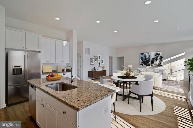 kitchen featuring white cabinetry, dark hardwood / wood-style floors, stainless steel appliances, a kitchen island with sink, and sink