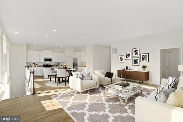 living room featuring a healthy amount of sunlight, sink, and light hardwood / wood-style flooring