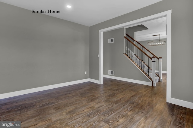 empty room with dark hardwood / wood-style floors and a notable chandelier