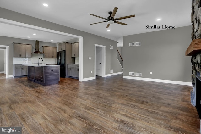 unfurnished living room with a fireplace, dark wood-type flooring, sink, and ceiling fan