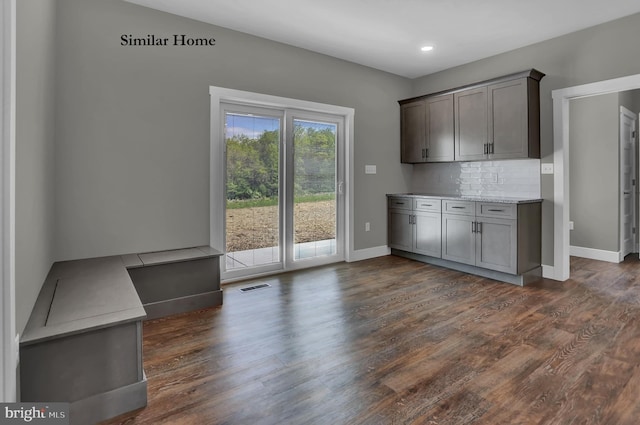 kitchen with light stone countertops, tasteful backsplash, and dark hardwood / wood-style flooring