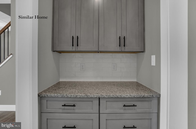 kitchen featuring tasteful backsplash, gray cabinets, light stone countertops, and wood-type flooring