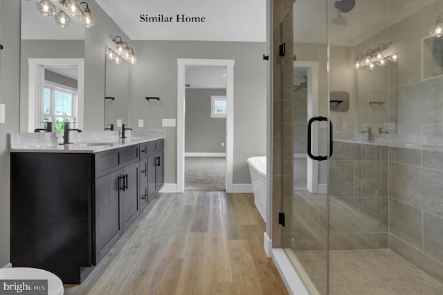 bathroom featuring large vanity, double sink, walk in shower, wood-type flooring, and an inviting chandelier