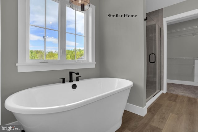 bathroom featuring a healthy amount of sunlight, plus walk in shower, and hardwood / wood-style floors