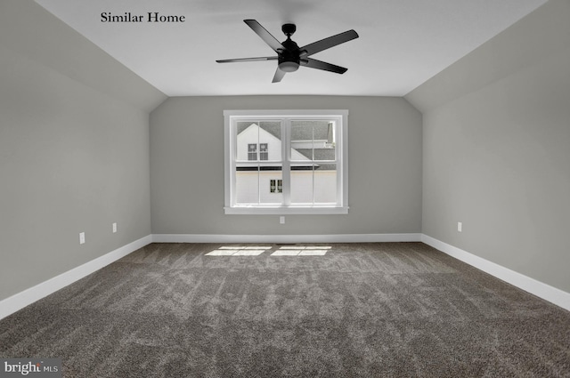 spare room with dark colored carpet, vaulted ceiling, and ceiling fan