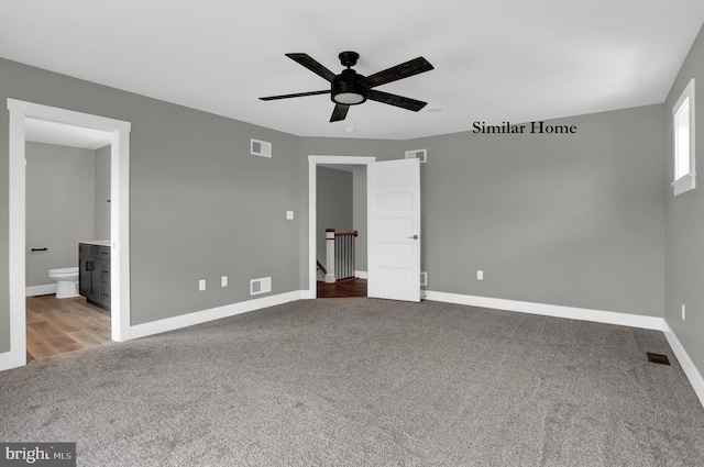 unfurnished bedroom with dark carpet, connected bathroom, and ceiling fan