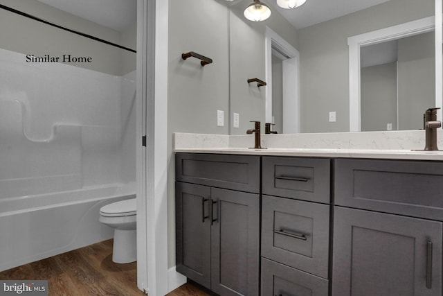 full bathroom featuring toilet, wood-type flooring, vanity with extensive cabinet space, and shower / tub combination