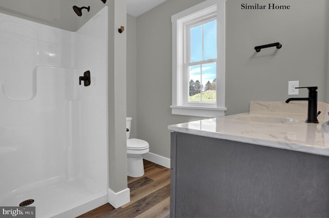 bathroom featuring hardwood / wood-style flooring, vanity, a shower, and toilet